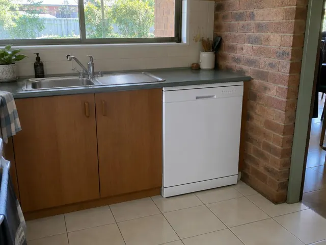 Built-in dishwasher under a kitchen counter beside a sink and brick wall in Maryland