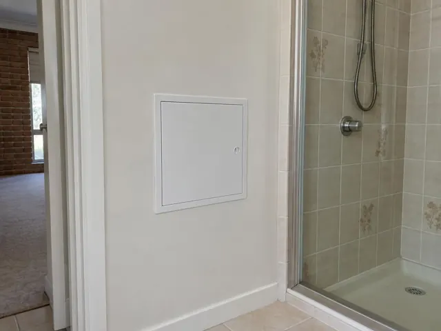 Neat white access panel beside a tiled shower in a home hallway in Maryland